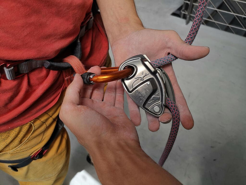 Partnercheck beim Klettern – Kontrolle des Karabiners zwischen Gurt und Sicherungsgerät Kletterer prüft beim Partnercheck den Karabiner zwischen Gurt und Sicherungsgerät – Symbol für Aufmerksamkeit und Sicherheit beim Klettern