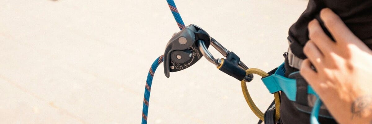 Grundausstattung Kletterausrüstung - Klettergurt, Sicherungsgerät & Kletterseil Ein Kletterer sichert Seinen Partner mit Sicherungsgerät und Seil