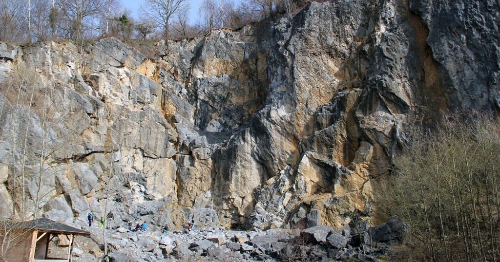 Kletterer an einer Felswand – typische Szene in einem Klettergebiet Kletterer an einer Felswand mit mehreren Routen – typisches Bild eines Klettergebiets im Freien