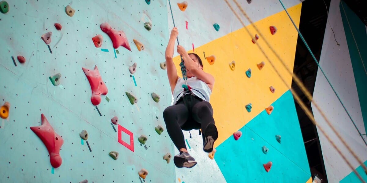 Einsteiger beim Klettern in der Halle beim Abseilen